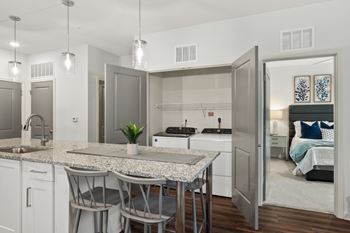 A modern kitchen with a marble table and a view into a bedroom.